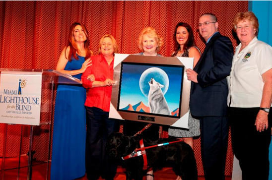 Jose Diaz of Robert M. Levy and Associates accepts tribute painting in memory of Bob Levy. Left to Right: Emcee Jade Alexander, U.S. Congresswoman Ileana Ros-Lehtinen, CEO Virginia Jacko, Florida State Senator Anitere Flores, Jose Diaz and Miami-Dade County Commissioner Sally Heyman