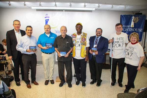 Emcee John Morales, Chet Jawor of Vanda Pharmaceuticals, Leo Manteca of MassMutual Miami, Lion Alan Campbell and Lion Jim Campbell representing Lions for the Blind, District Administrator of the Florida Division of Blind Services Juan Carlos Diaz, Paul Schroeder of Aira and CEO Virginia Jacko.