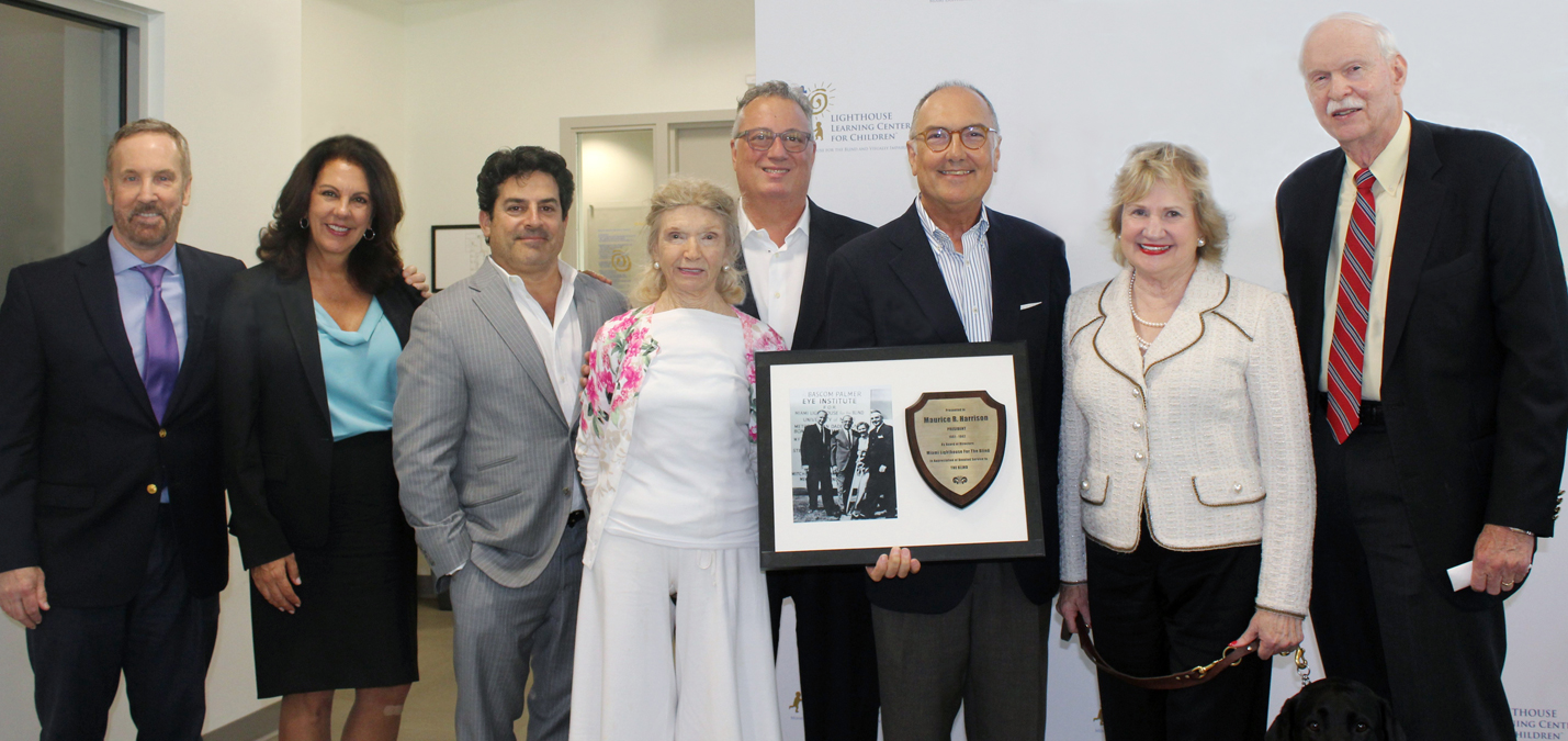 Miami Lighthouse Board Directors Dr. Thomas Johnson, Donna Abood, Alfred Karram, Angela Whitman, Board Chair Louis Nostro, President and CEO Virginia Jacko and Dr. Harry Flynn present tribute of original photo of Bascom Palmer Eye Institute building groundbreaking to BPEI Chair Dr. Eduardo Alfonso
